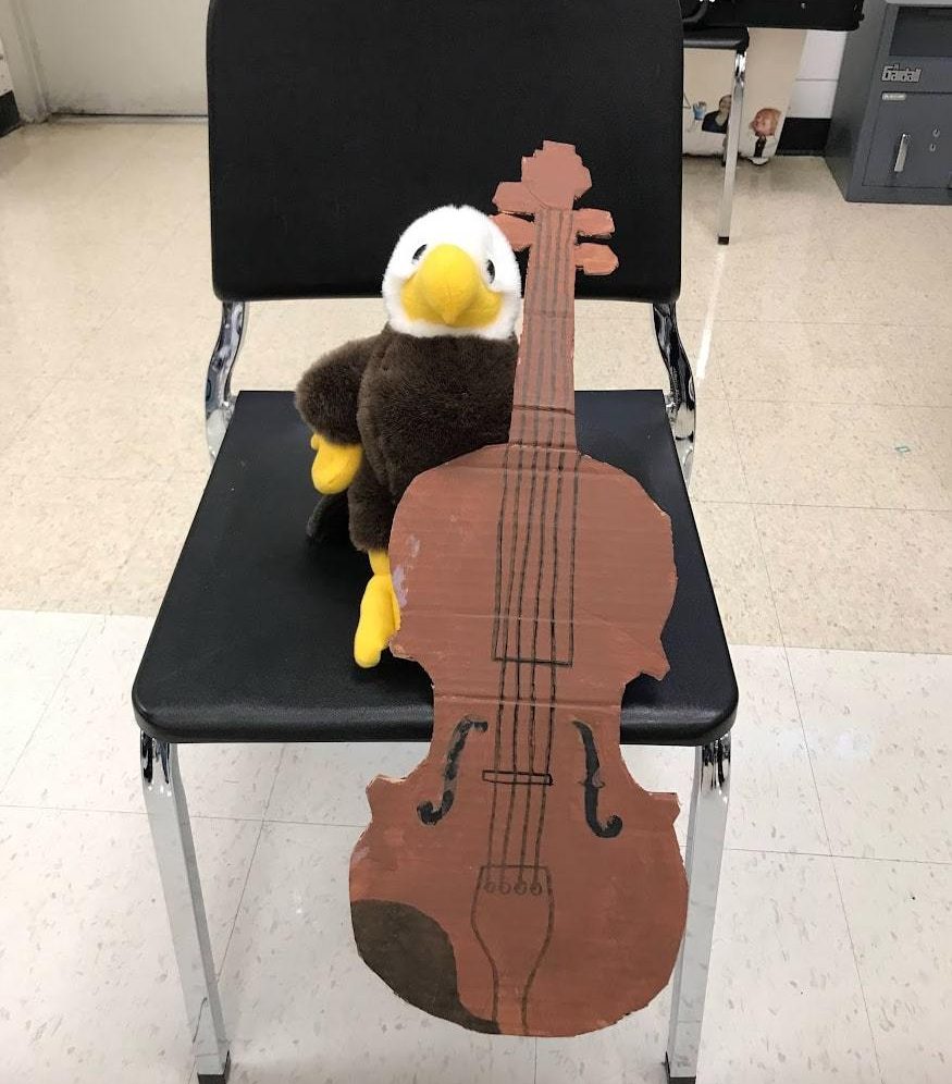 Skeagle the Eagle practices music with its cardboard cello. Credit: J. Chou. 