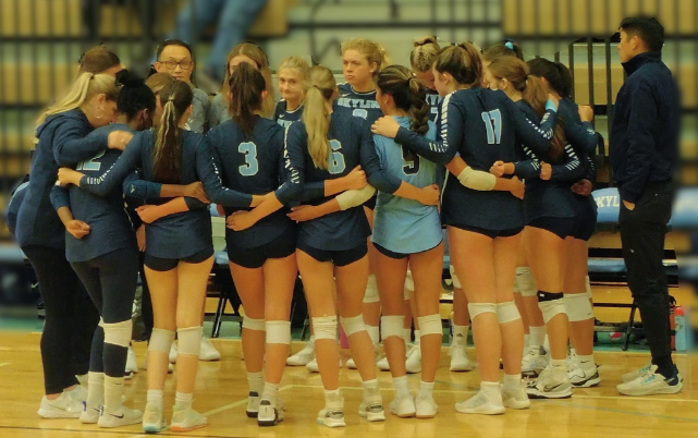 Varsity Volleyball regroups in their huddle for a major come back. Credit: M. Kilbride.
