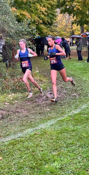 Irie Jane (‘27) and Becca Van Lent running through mud at a cross country race. Credit: Coleen Van Lent