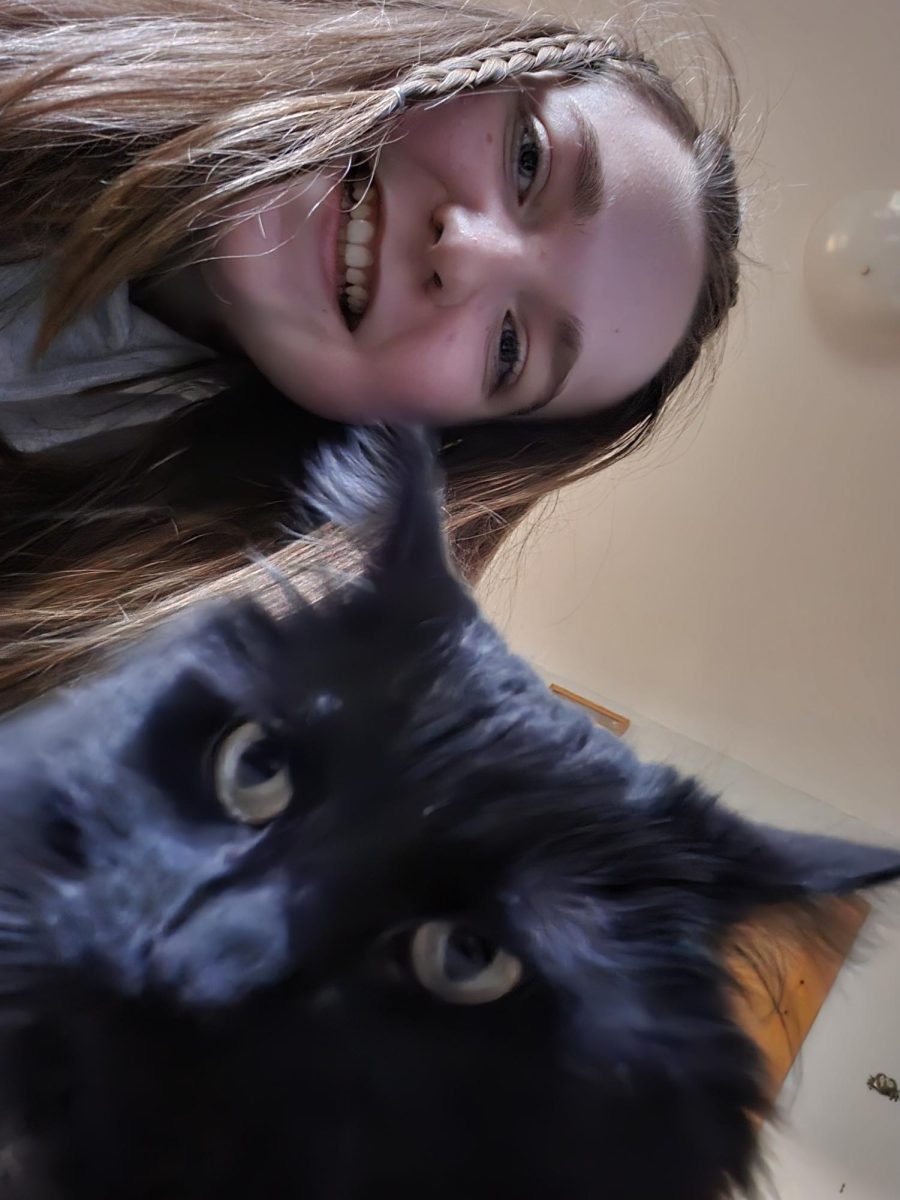 Kylie Dybdahl ('26) taking a photo with her cat, Cookie. 