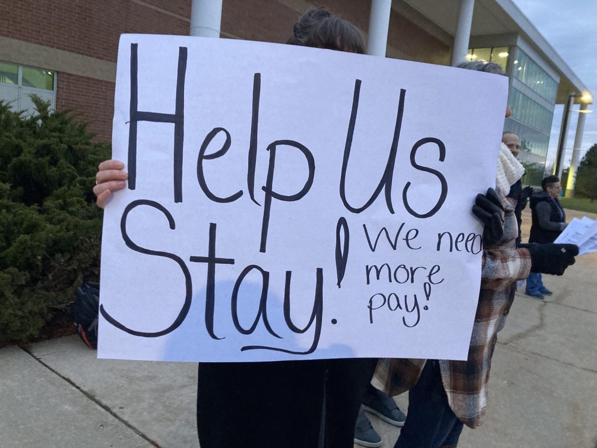 Teacher holding up sign with AAEA Action Team slogan, "Help Us Stay."