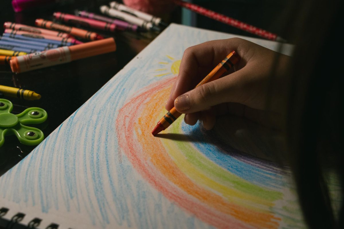 A girl finishes her rainbow drawing by adding some finishing touches.