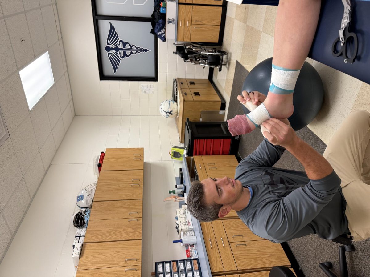 Eric Kilpatrick wrapping an athlete's foot.