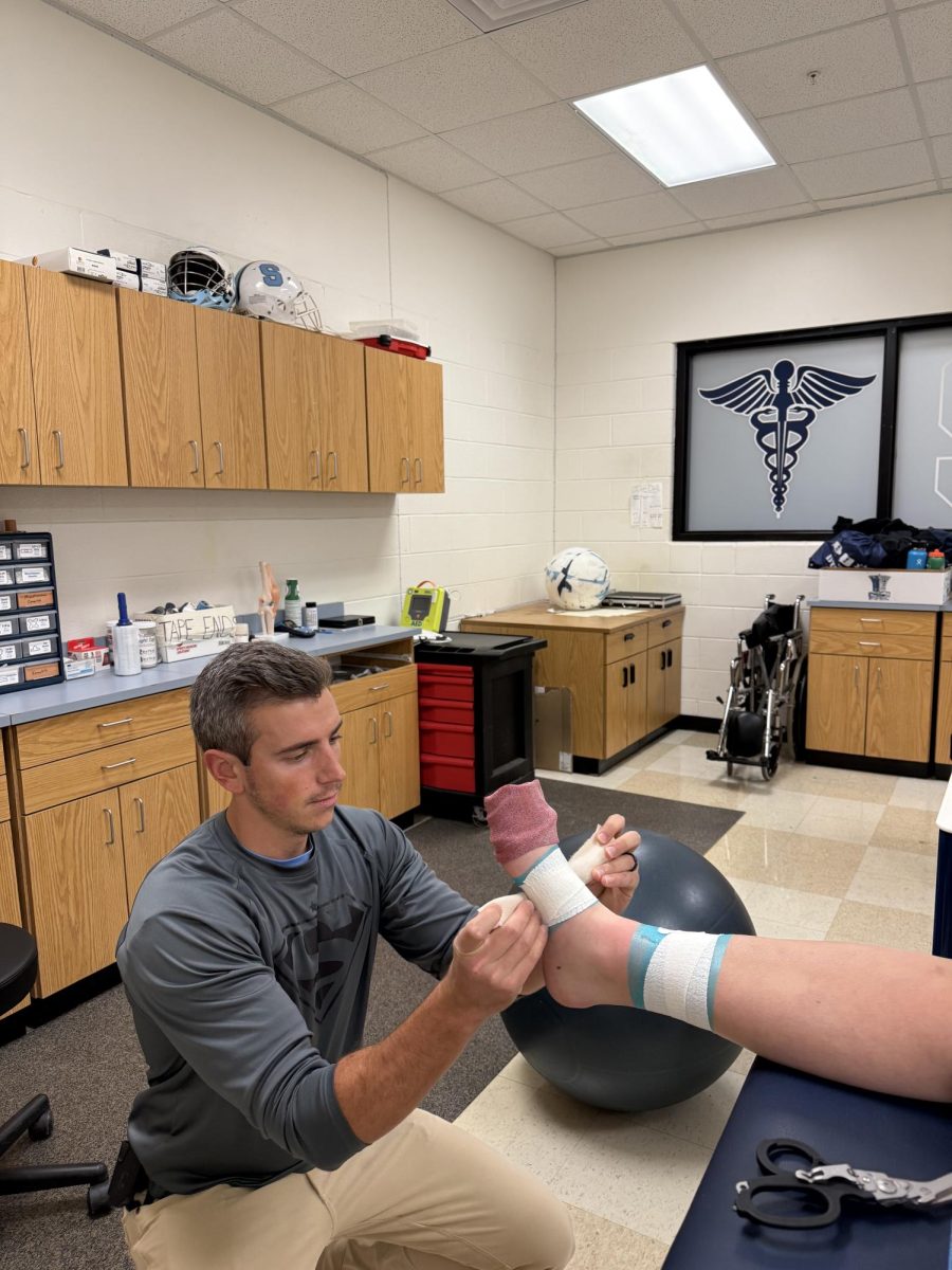 Eric Kilpatrick wrapping an athlete's foot.