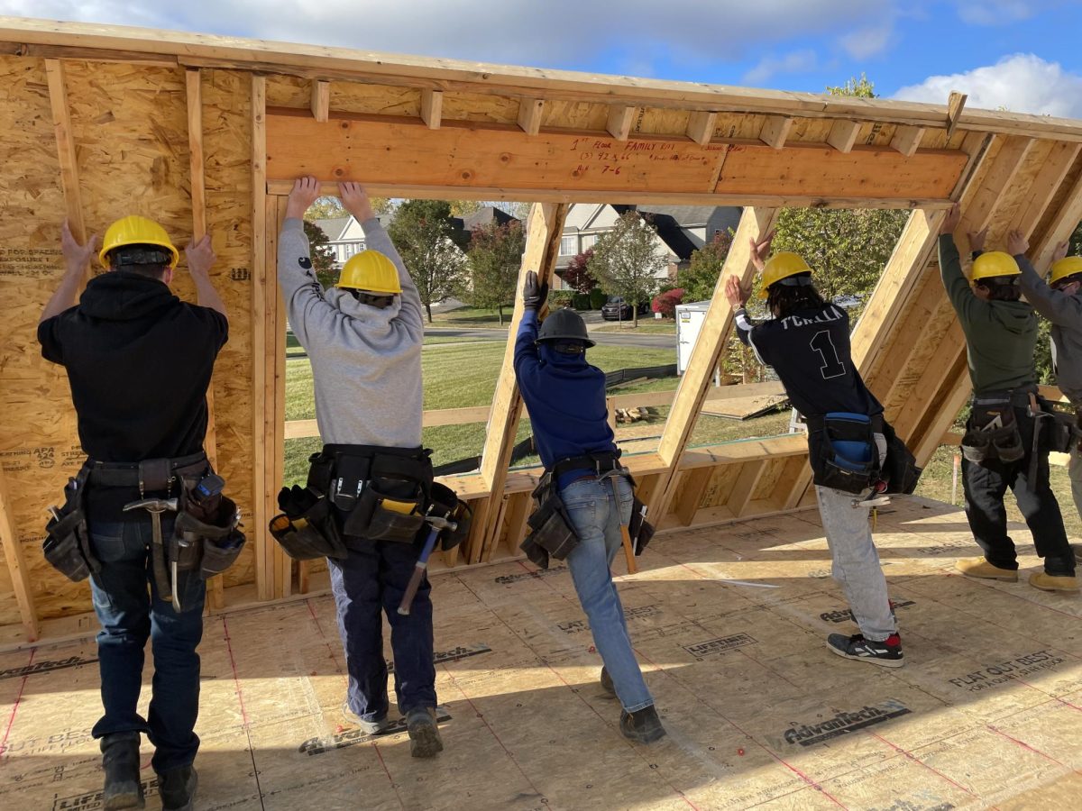 Homebuilding students in team 55 raise part of the first floor back wall.