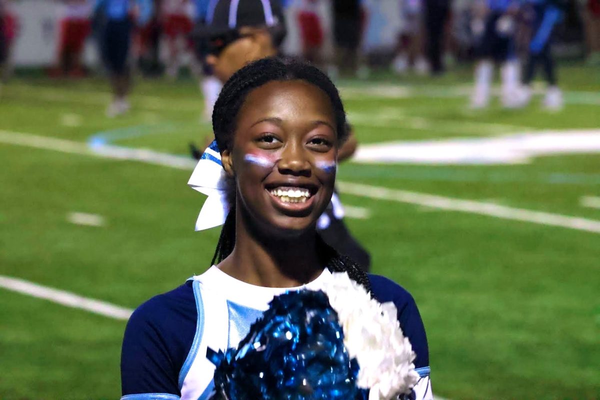 Junior Maya Neblett is cheering for the Skyline Pompon team at a high school football game.