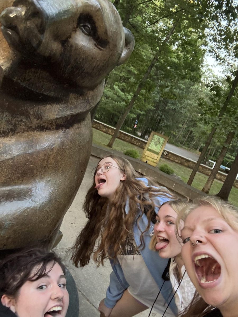 Norah DeRosia ('26), Claire Hurley ('26), Soph McClatchey ('26), and Eleanor Wing ('26) pretend to lick the bear statue at the Interlochen Center for the Arts.